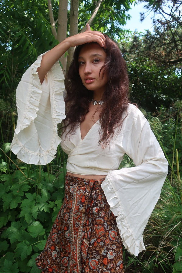 Model wears our beautiful boho bell sleeve wrap top with 70's inspired frill trim in a elegant cream coconut white by All About Audrey