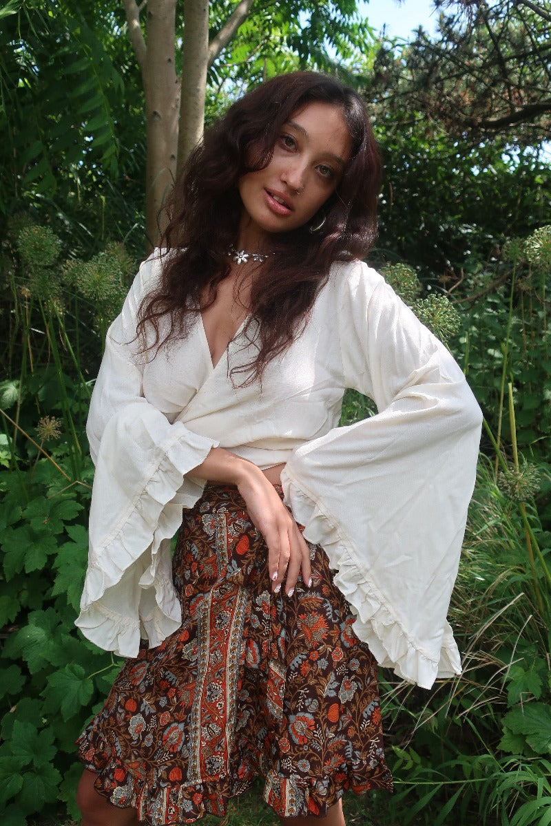 Model wears our beautiful boho bell sleeve wrap top with 70's inspired frill trim in a elegant cream coconut white by All About Audrey