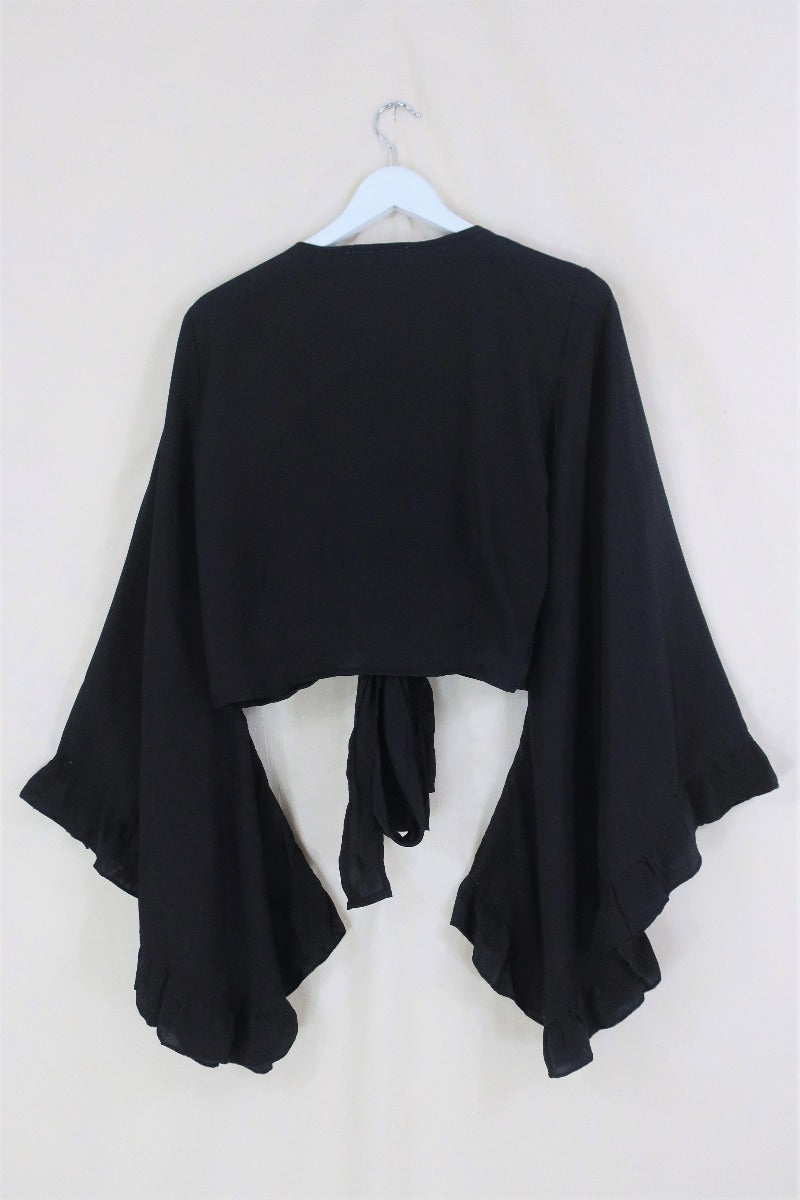 Flat lay of our Venus Khroma wrap top in Vampy Black. Classic black tone that's easy to style. Inspired by 70's bohemia by All About Audrey