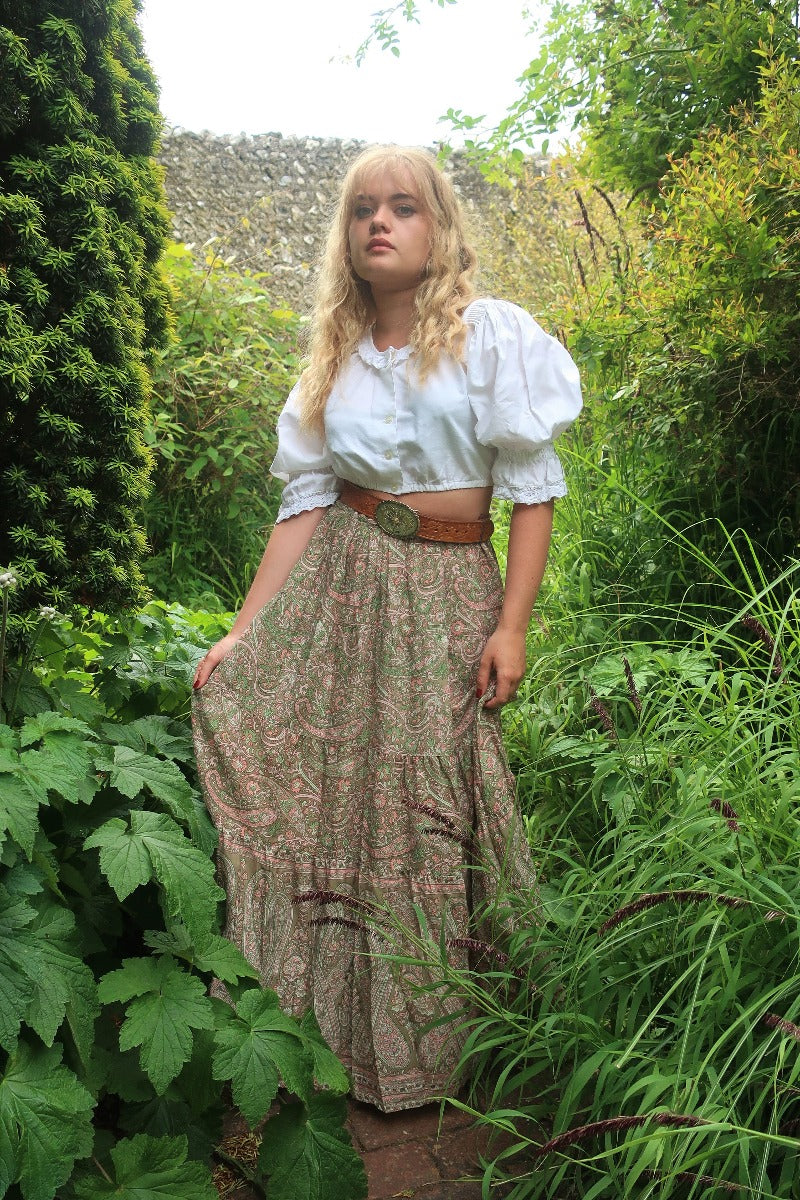 Model wears our Florence prairie skirt in Sage & Blush. Inspired by 1970s bohemian style by All About Audrey