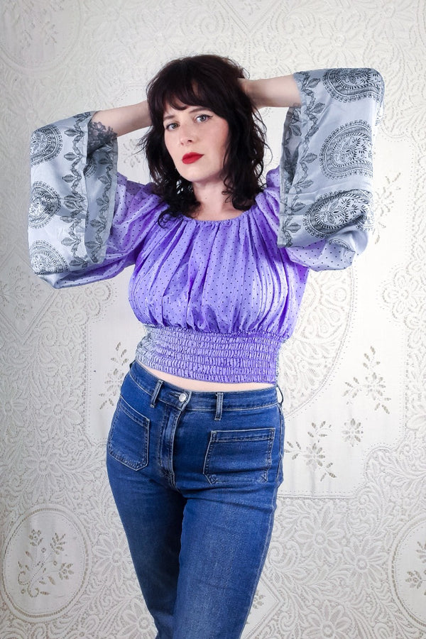 Our gorgeous model shows a front view of our Scorpio top. This beauty has a small arrow head print design, incorporated with a large paisley print on the floaty sleeves in tones of sliver and lilac. 
