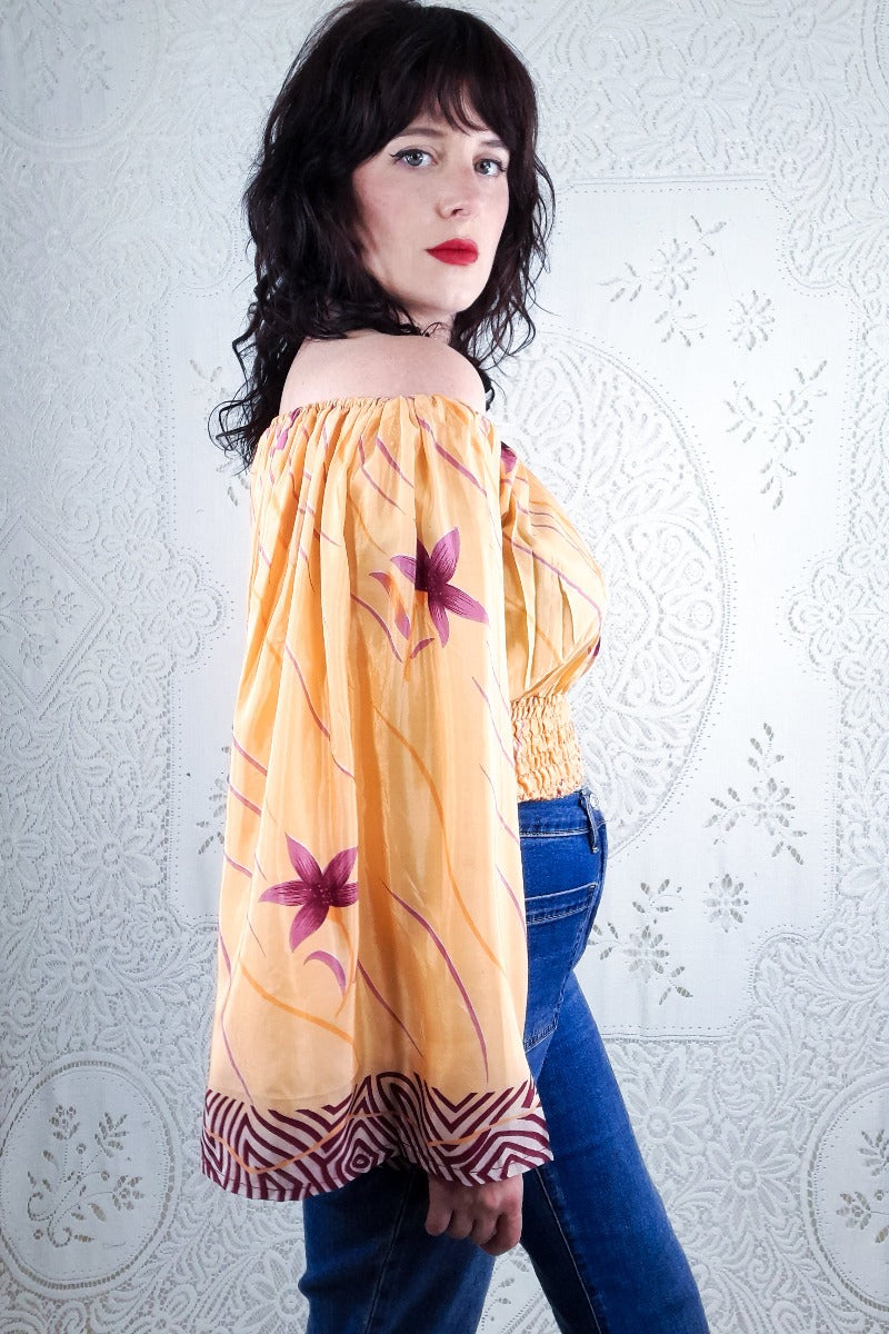 Our stunning model shows a close up of the print on the sleeve of our beautiful Bardot Scorpio top. This gorgeous top features a violet lotus print with a peachy tone background. 