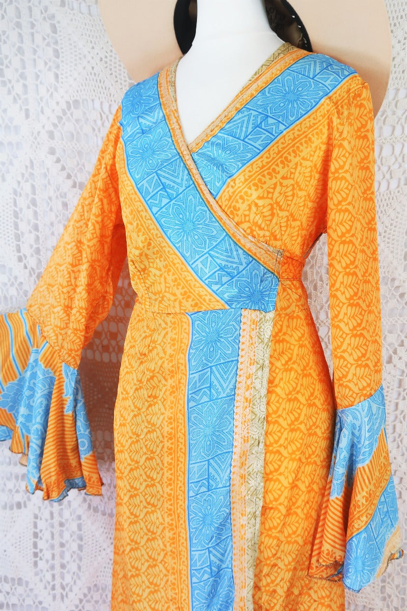 close up on bust of boho wrap dress with apricot orange fern leaf print with powdered blue Grecian tile print stripes