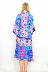 Full length photo shows the back of the kimono as a midi length wrap dress displaying the size of the print being bigger at the hem of the kimono than the nape of the neck.