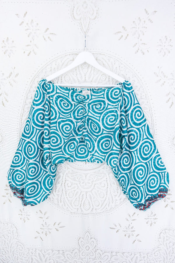 Front view of this groovy Ariel top. Covered in psychedelic swirls in tones of icy white and teal. Chilli red detailing on the cuffs.  
