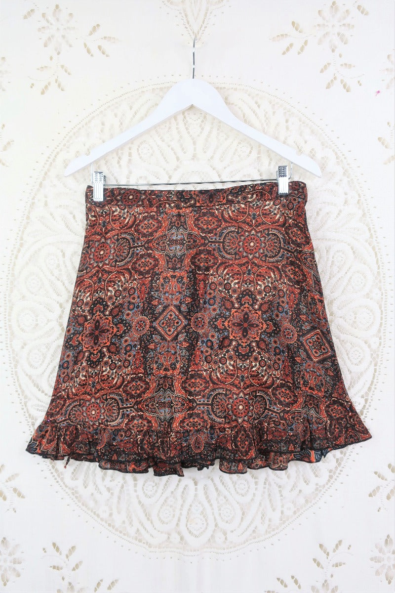 Photo shows Venus mini wrap skirt flaylay featuring frills and a boho dark earth tone psychedelic colourway All About Audrey