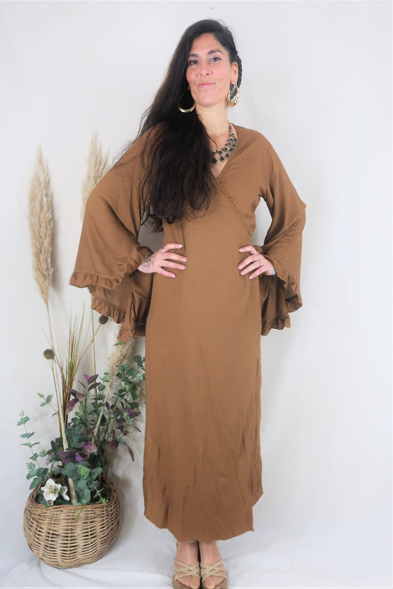 Full shot of model wearing the Venus maxi wrap dress, with floaty hippie ruffle bell sleeves in a soft rayon fabric in a earthy brown tone by all about audrey
