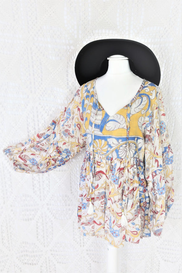 Photo shows mannequin wearing our Daisy cotton smock top in a boho peacock block print design with balloon sleeves and a tie neckline. 