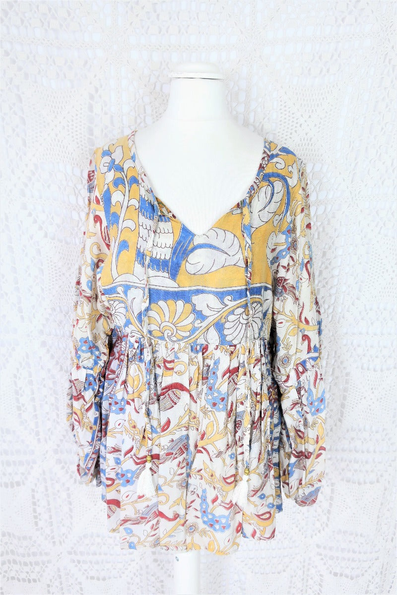 Photo shows mannequin wearing our Daisy cotton smock top in a boho peacock block print design with balloon sleeves and a tie neckline.