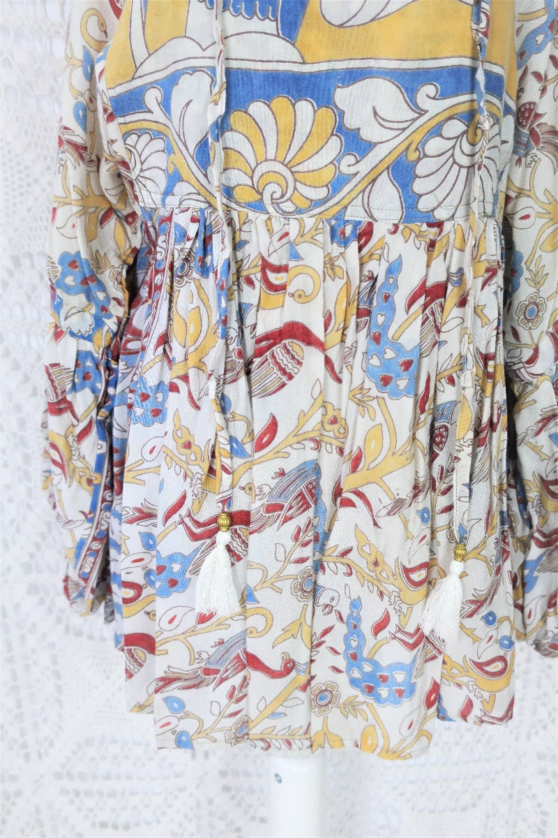Photo shows close up of mannequin wearing our Daisy cotton smock top in a boho peacock block print design with balloon sleeves and a tie neckline.