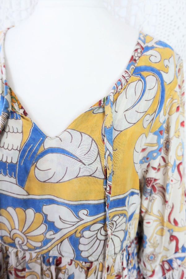 Photo shows close up of mannequin wearing our Daisy cotton smock top in a boho peacock block print design with balloon sleeves and a tie neckline.