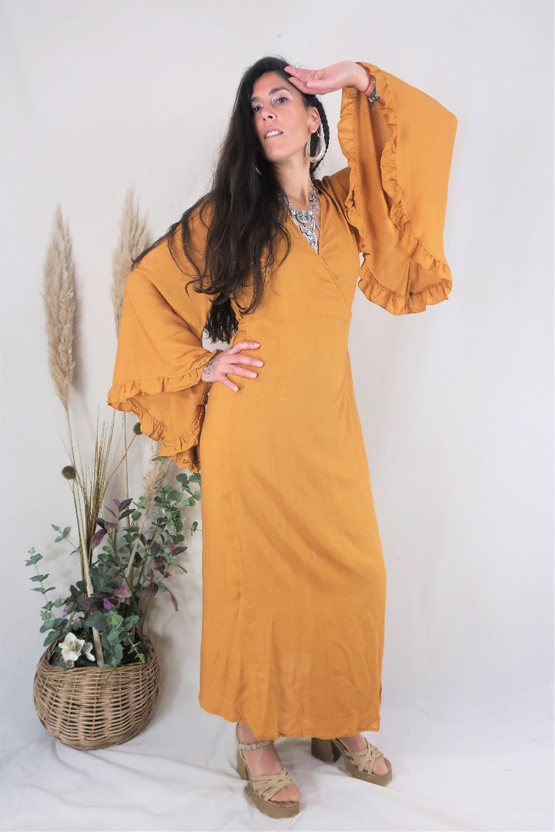 Model wears Venus maxi wrap dress in Mustard Yellow rayon fabric. Beautiful floaty oversized butterfly sleeves and an adjustable waist by All About Audrey