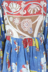 Photo shows back of  a deep blue peacock and hand gesture block printed boho smock top with a tie neck and balloon sleeves.