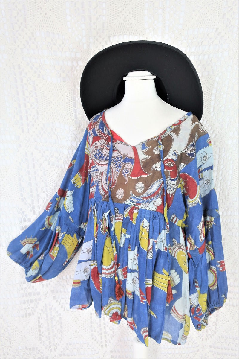 Photo shows a deep blue peacock and hand gesture block printed boho smock top with a tie neck and balloon sleeves.