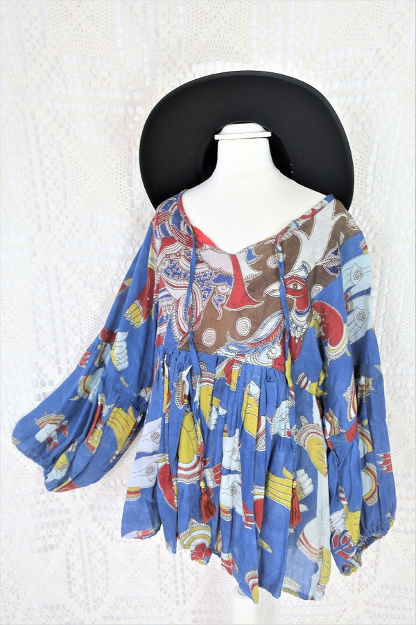 Photo shows a deep blue peacock and hand gesture block printed boho smock top with a tie neck and balloon sleeves.