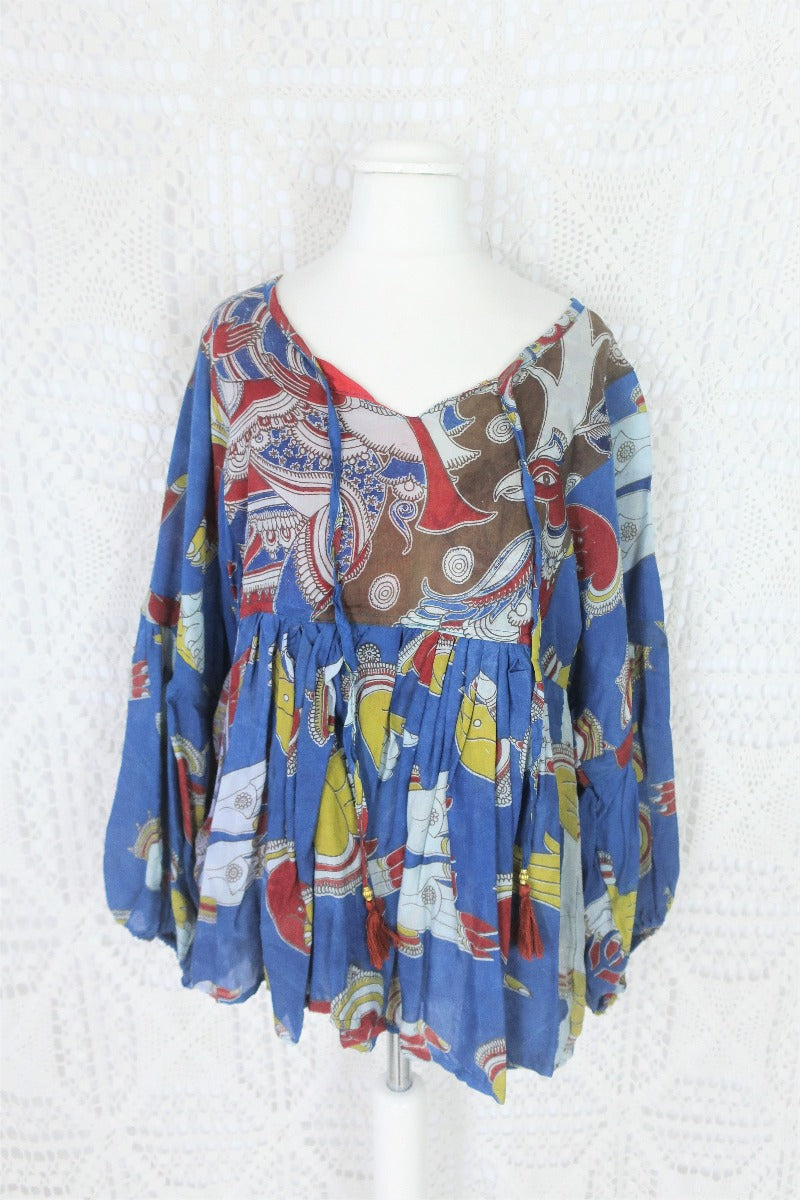 Photo shows a deep blue peacock and hand gesture block printed boho smock top with a tie neck and balloon sleeves.