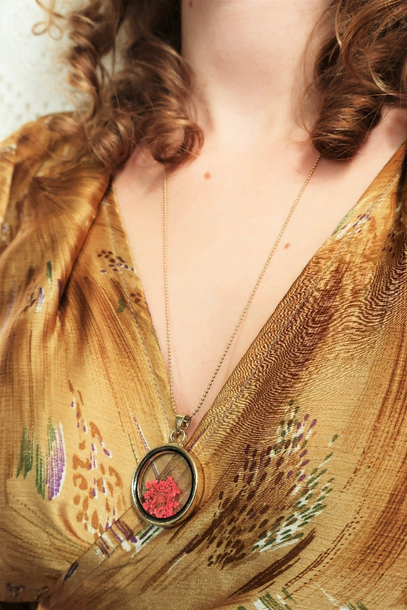 close up model wears boho pressed flower pendant in gold colour on long chain from our collection of vintage inspired jewellery by all about audrey
