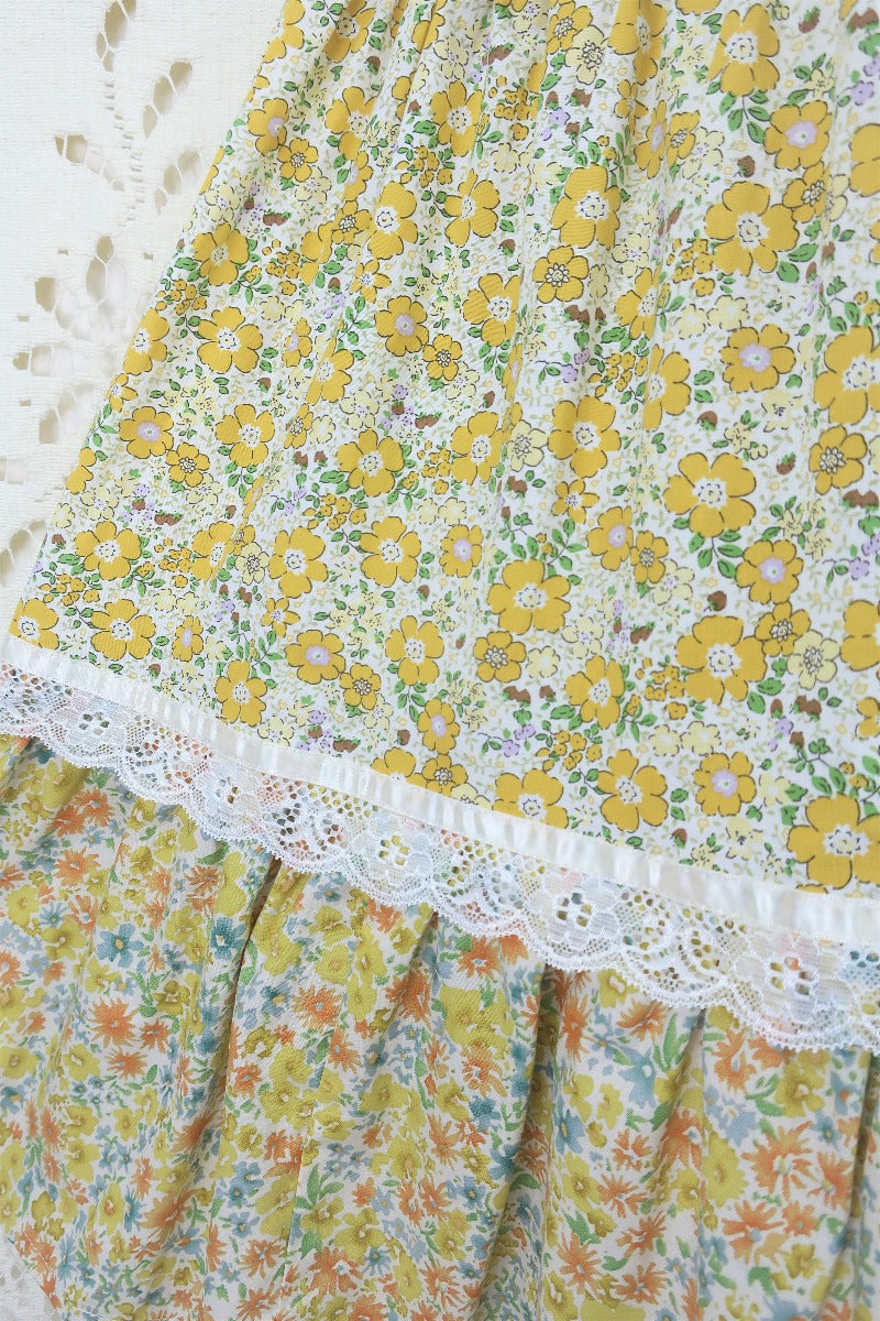Extreme close up of dress fabrics. Showing two of the bohemian retro inspired prairie ditsy floral prints in yellow separated by lace By All About Audrey