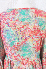 Photo shows back close up of Daisy smock cotton top in a deep coral pink and aqua colourway and abstract print. Balloon style sleeves and a tie neck top.