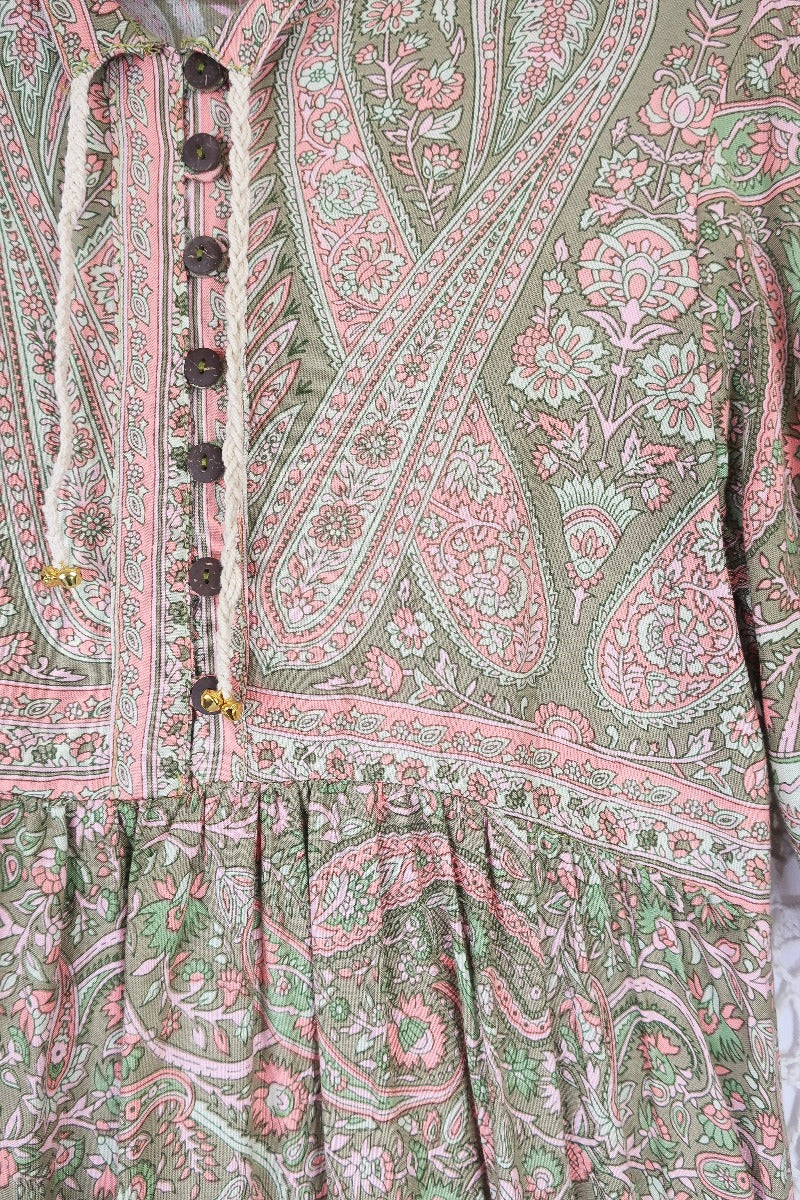detail image of the floral and paisley printed fabric showin in light pink and sage and mint green colours with button down peasant style top and rope necktie florence dress by all about audrey