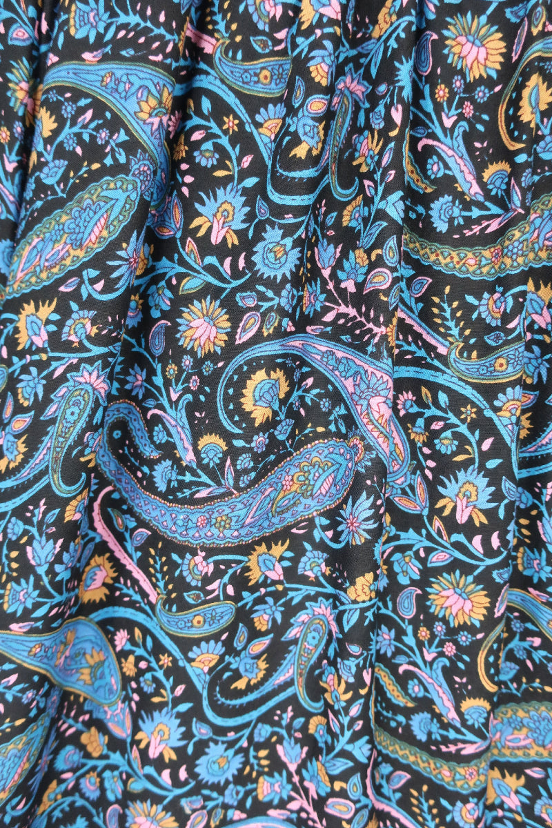 close up detail of flower and paisley print on florence balloon sleeve smocked mini dress in black with blue and pink by all about audrey