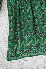 close up of contrast design hemline on indian peacock printed primrose midi length dress in forest green with exaggerated balloon sleeve in 1970s vintage inspired bohemian style by all about audrey