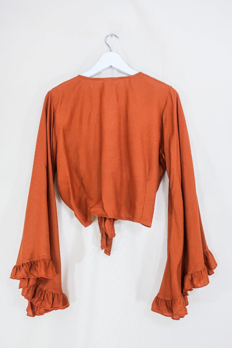 Flatlay photo of our Khroma Venus Wrap Top in Red Clay by All About Audrey