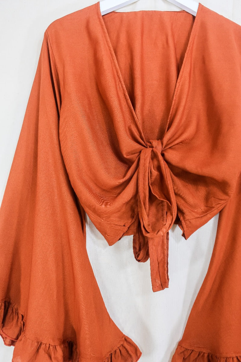 Flatlay photo of our Khroma Venus Wrap Top in Red Clay by All About Audrey