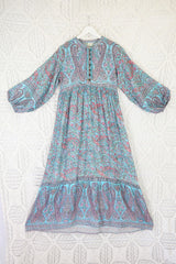 product shot of florence maxi dress laid flat to show balloon sleeve with drop hemline and smocked style button down top with high neck and rope tie in blue and pink paisley design by all about audrey