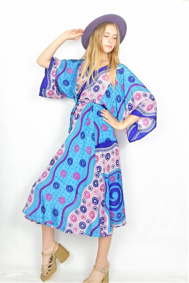 Full length photo shows model wearing turquoise kimono in as a midi wraparound dress using the adjustable ties.
