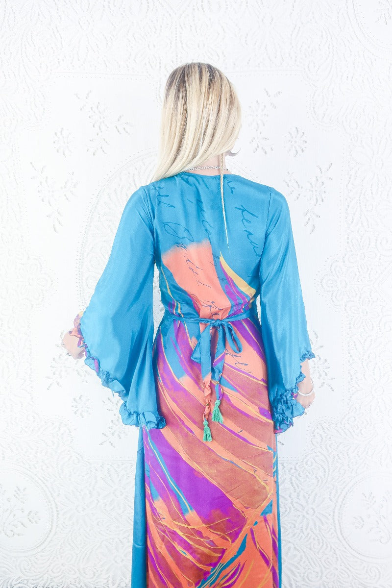 Model shows back view of our Venus maxi wrap dress. Wrap dress design with floaty bell sleeves. By All About Audrey.