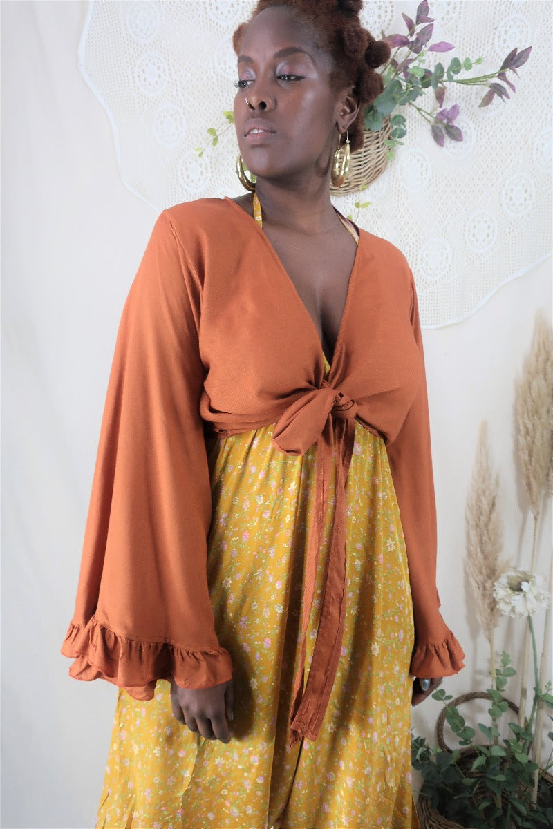Model wears our bohemian 70s inspired khroma Venus wrap top in an earthy clay colour and shows of the long length butterfly sleeves by all about audrey