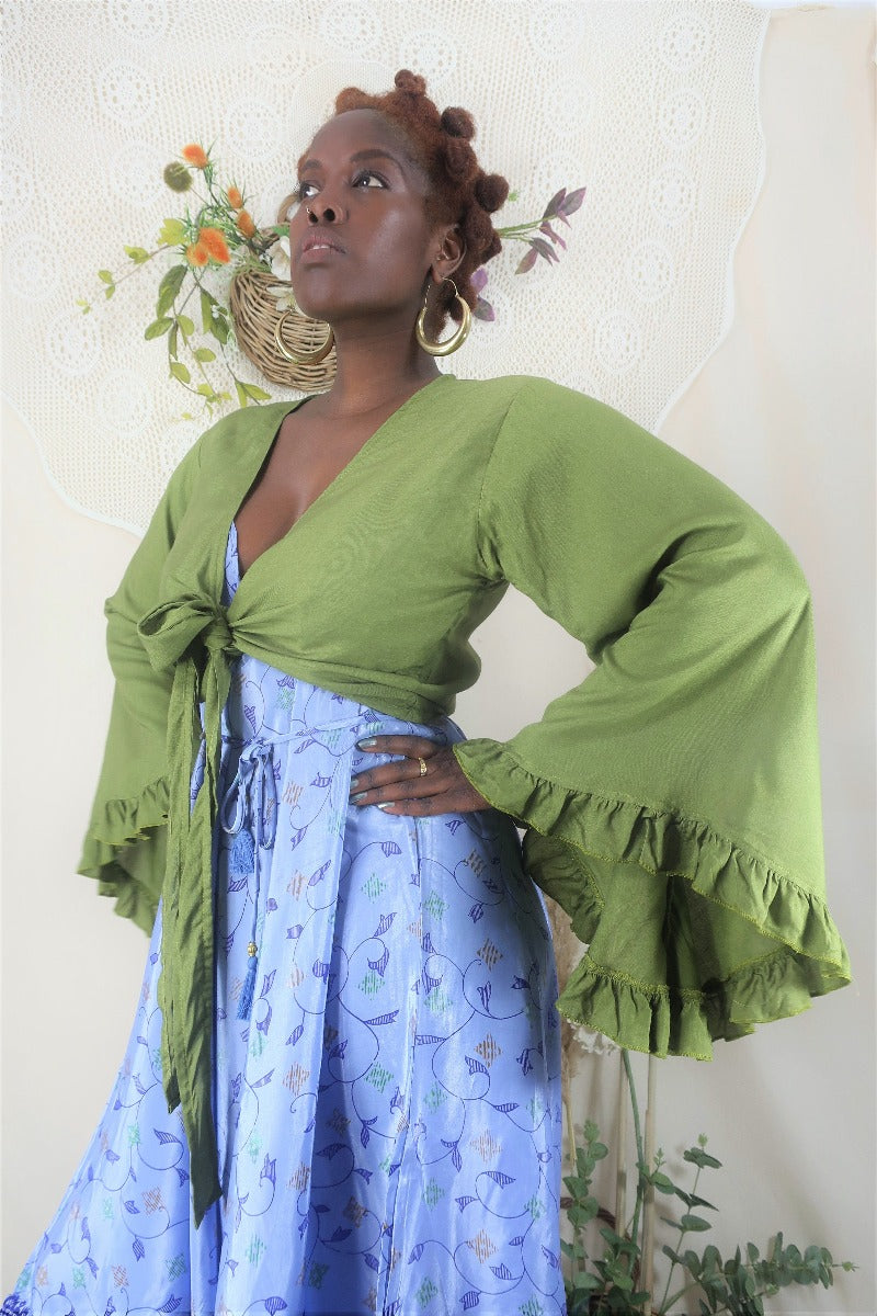 model wears our Venus top in pixie green tied at the front and shows of the frilly butterfly 70s inspired bell sleeves