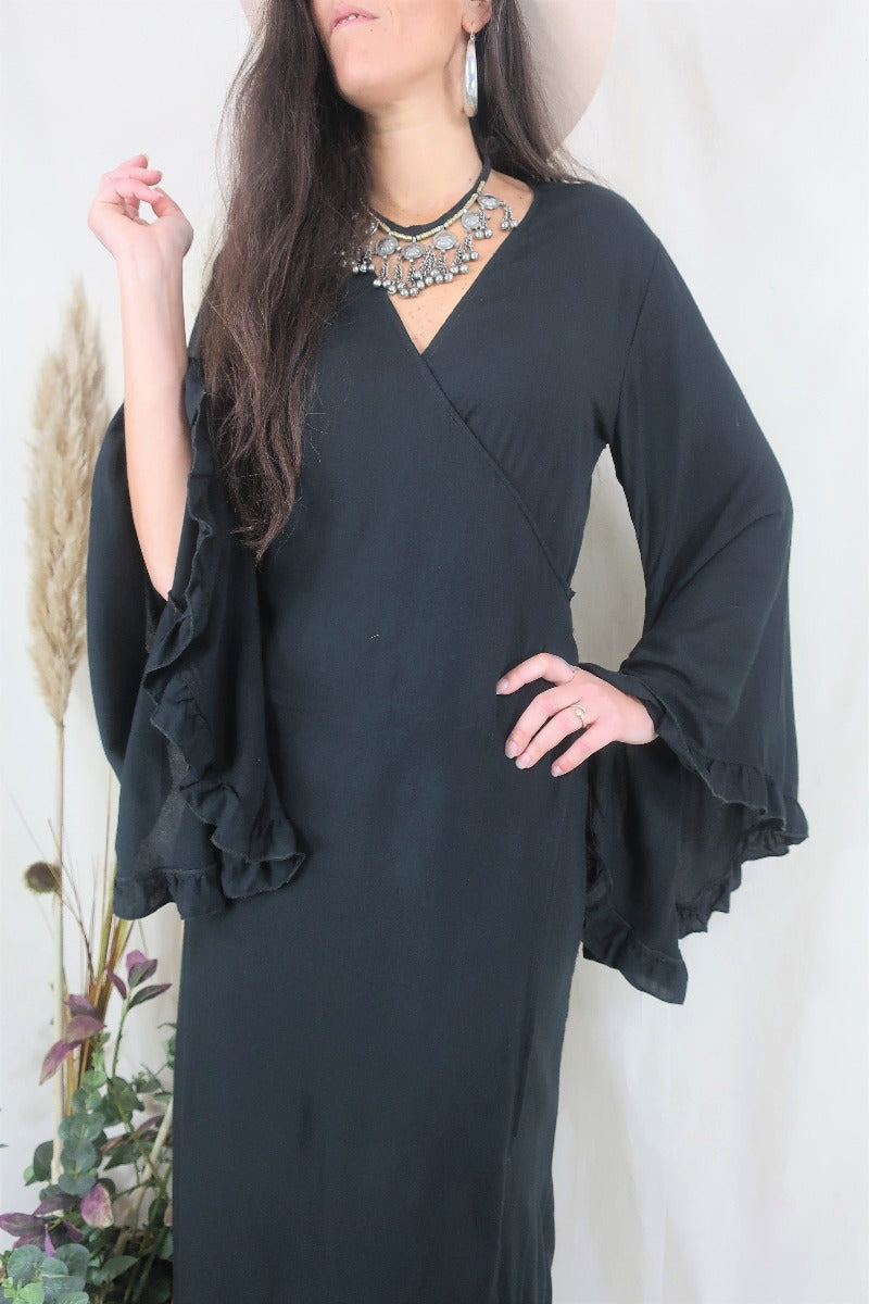 Close up of Venus maxi wrap dress in Nightshade Black, showing off the long oversized floaty ruffle bell sleeves by All About Audrey
