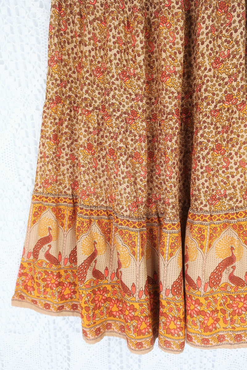 detail showing contrast hemline on model wears peacock prairie maxi skirt in tan and turmeric indian style printed sustainable rayon all about audrey