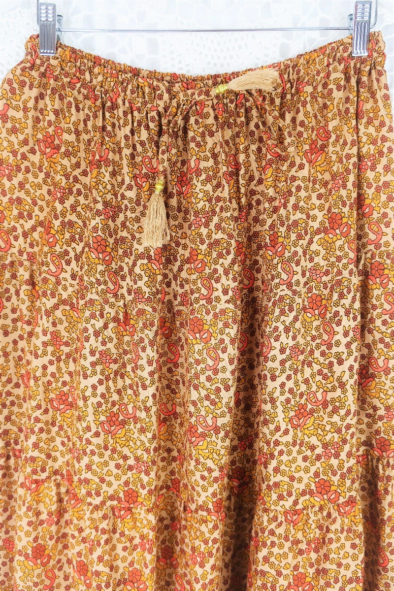 close up to show colour print and drawstring waist with tassel ties on model wears peacock prairie maxi skirt in tan and turmeric indian style printed sustainable rayon all about audrey