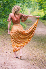 back view on model model wears peacock prairie maxi skirt in tan and turmeric indian style printed sustainable rayon all about audrey