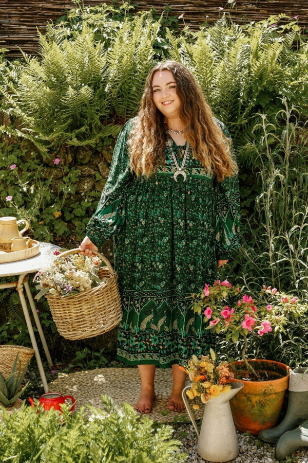 model wears indian peacock printed primrose midi length dress in forest green with exaggerated balloon sleeve in 1970s vintage inspired bohemian style by all about audrey