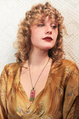 model wears pink dried flower pendant in brass rectangle shape on chain from our vintage inspired jewellery and gifts collection by all about audrey