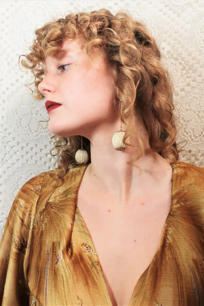 side view model wears rattan woven ball pendant dangly earrings from our collection of vintage style and bohemian jewellery at all about audrey
