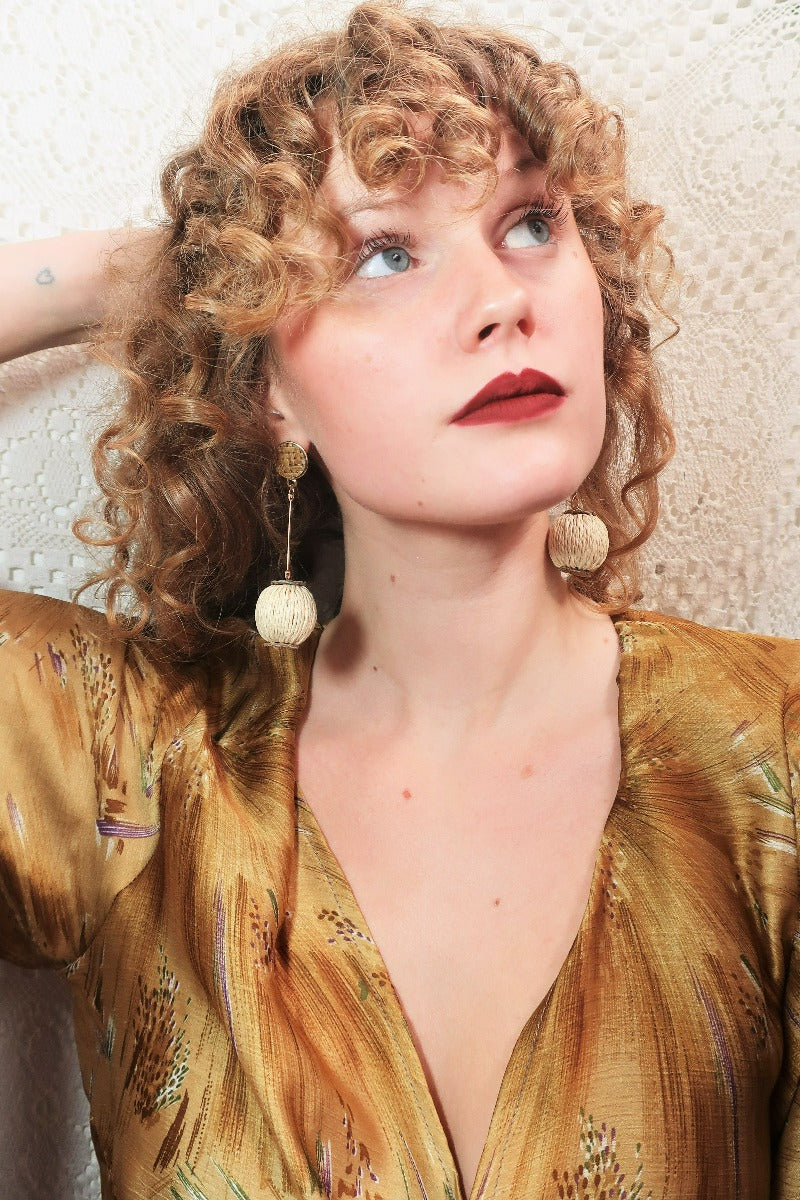 model wears rattan woven ball pendant dangly earrings from our collection of vintage style and bohemian jewellery at all about audrey