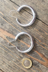 laid flat next to coin for scale medium silver painted thin hoops from our collection of vintage inspired bohemian jewellery and accessories by all about audrey